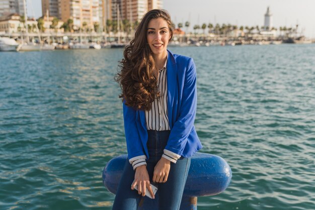 Foto gratuita mujer joven feliz posando con el mar de fondo