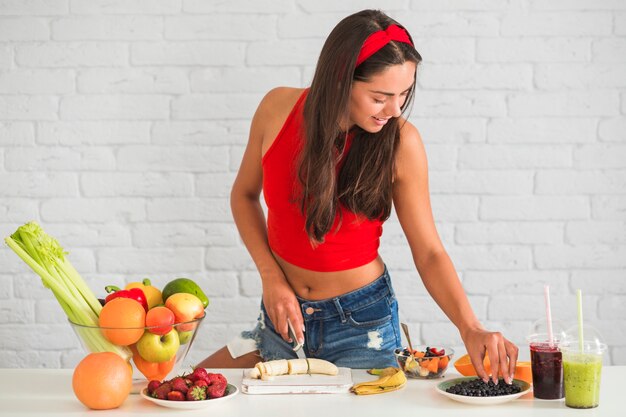 Mujer joven feliz preparando ensalada de frutas y verduras