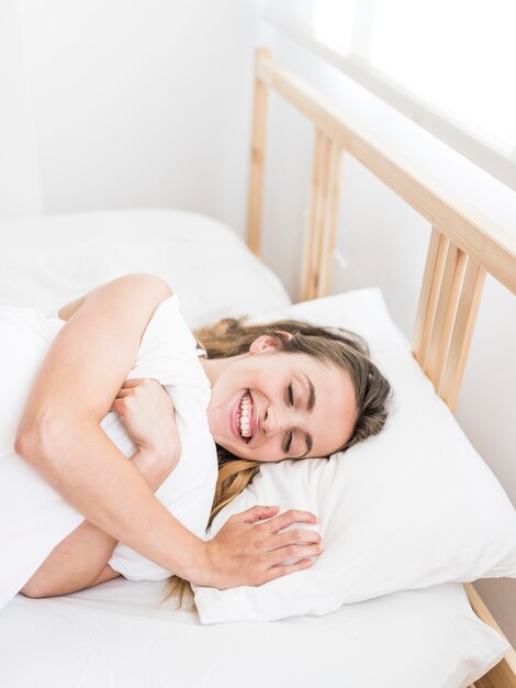 Mujer joven feliz que miente en cama