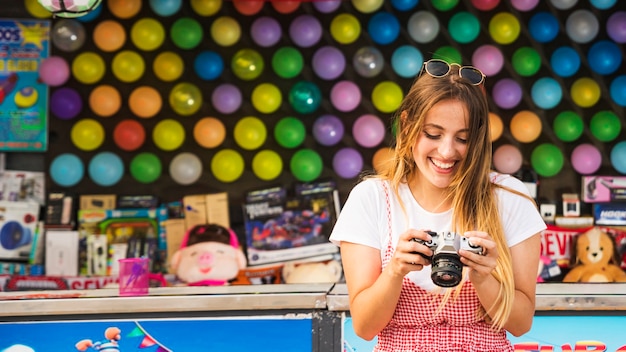 Mujer joven feliz que mira en cámara el parque de atracciones