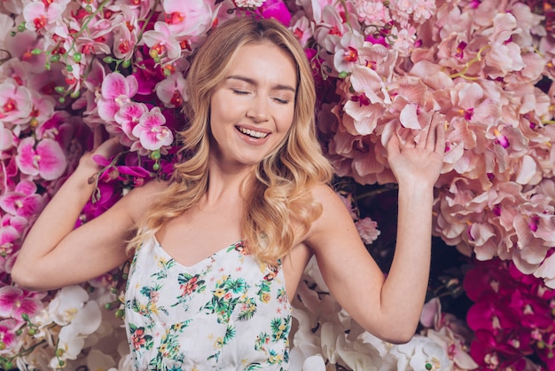 Foto gratuita mujer joven feliz que siente relajada con las ramas de una orquídea florece