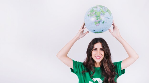 Mujer joven feliz que sostiene el globo sobre su cabeza