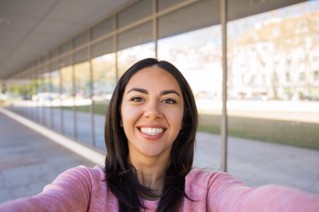 Mujer joven feliz que toma la foto del selfie al aire libre