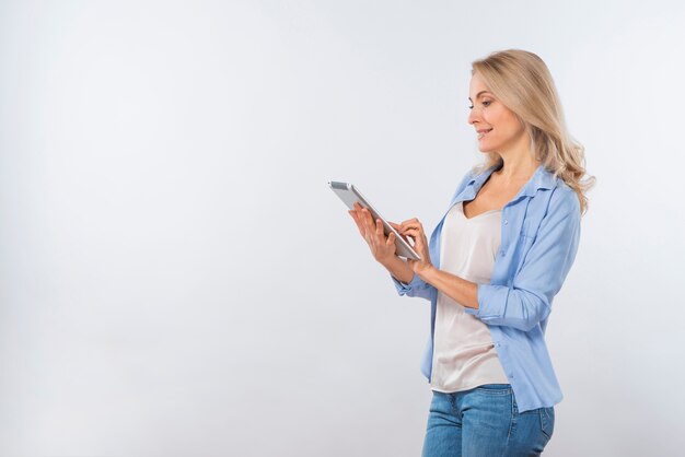 Mujer joven feliz que usa la tableta digital aislada en el fondo blanco