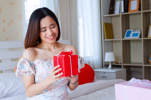 Mujer joven feliz con rojo presente en el dormitorio