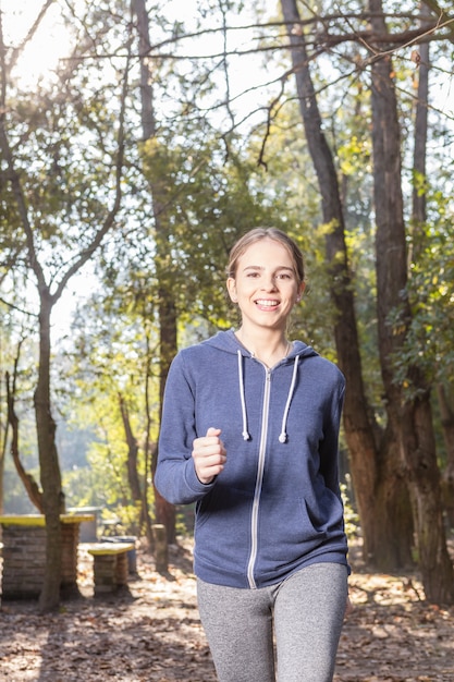 Mujer joven feliz con ropa deportiva corriendo en el parque