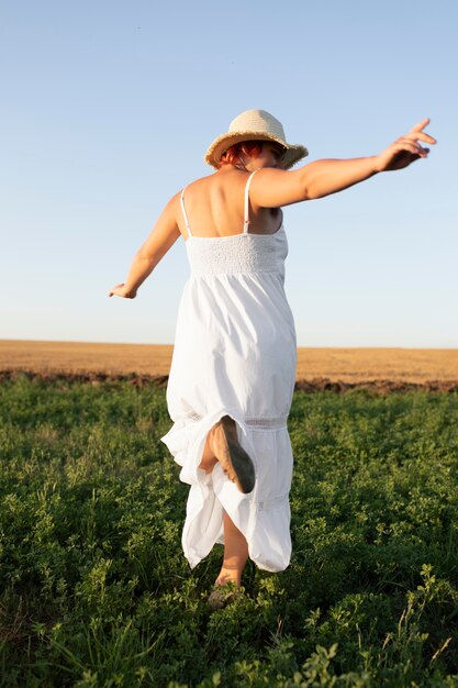 Mujer joven feliz saltando en un campo al aire libre