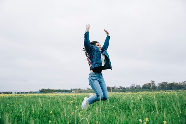 Mujer joven feliz saltando en el campo