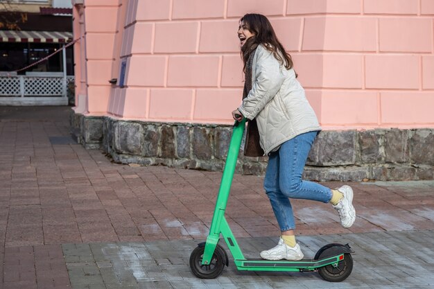Mujer joven feliz en scooter eléctrico en la ciudad.