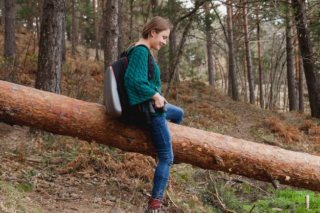 Mujer joven feliz sentada en un tronco
