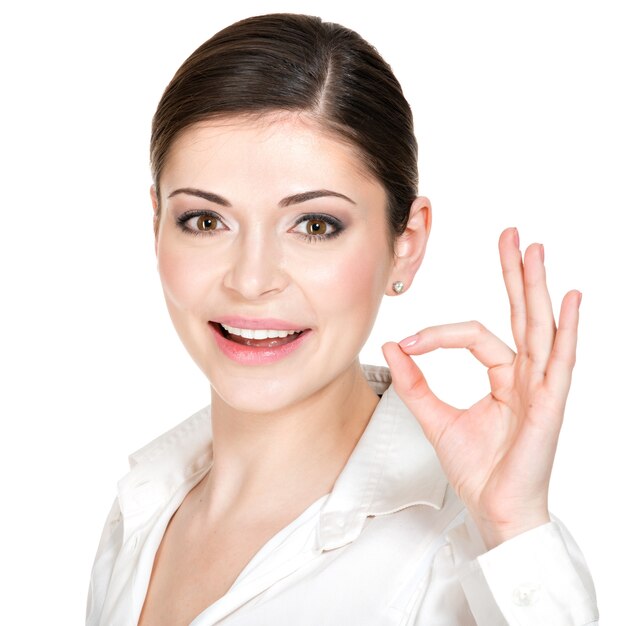 Mujer joven feliz con signo ok en camisa blanca.