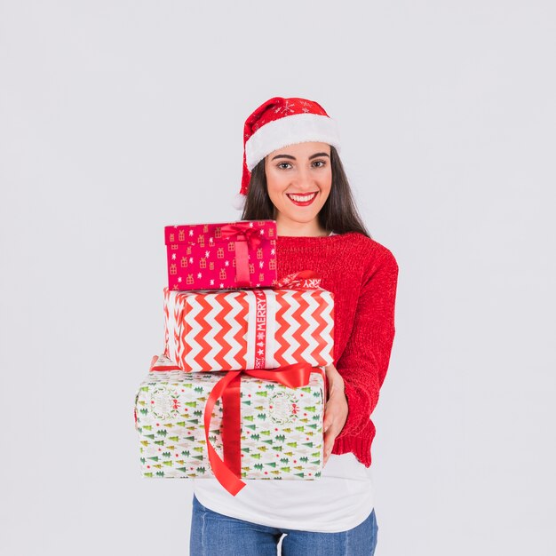 Mujer joven feliz en el sombrero de la Navidad y cajas presentes