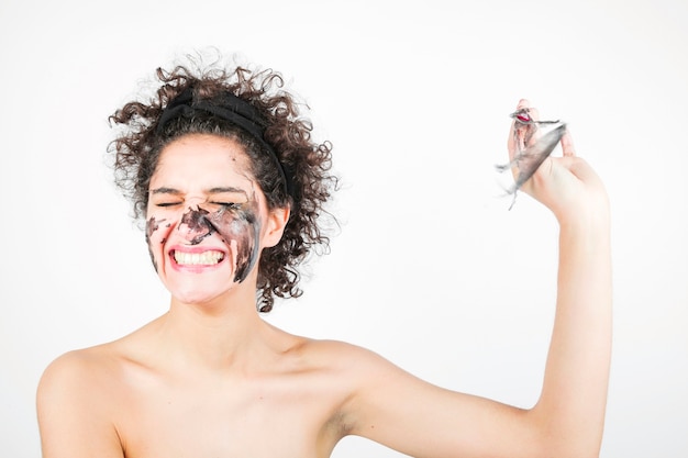 Foto gratuita mujer joven feliz sonriente que quita la máscara facial contra el fondo blanco