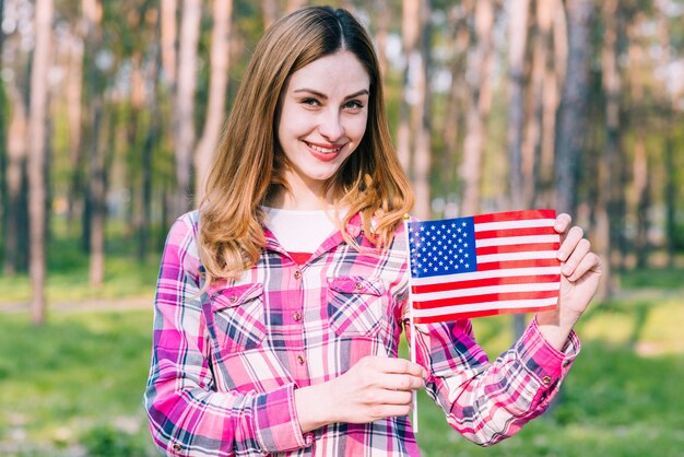 Mujer joven feliz sosteniendo la bandera de Estados Unidos