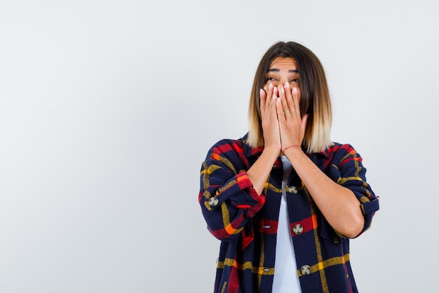 Foto gratuita mujer joven feliz sosteniendo sus manos en su boca sobre fondo blanco.