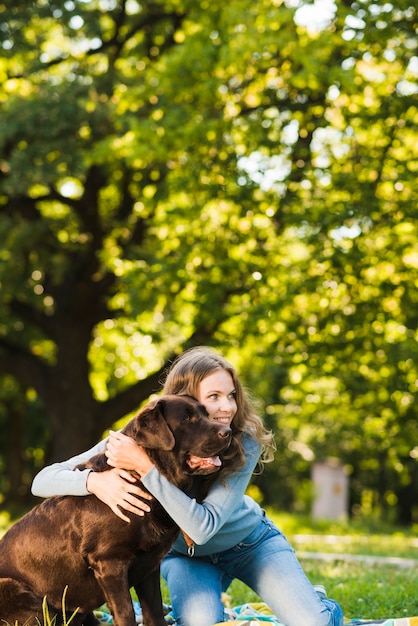 Foto gratuita mujer joven feliz con su perro en el parque