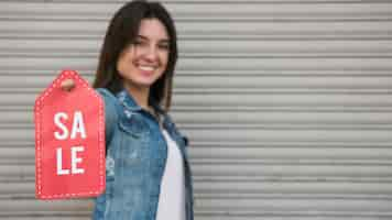 Foto gratuita mujer joven feliz con la tableta de la venta cerca de la pared que cubre perfilada