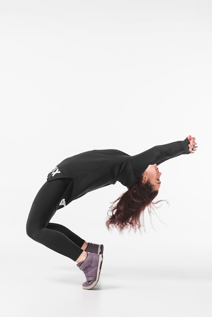 Mujer joven flexible bailando contra el telón de fondo blanco