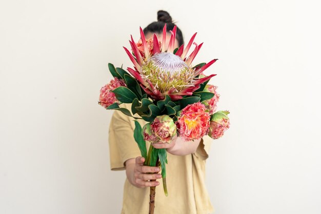 Una mujer joven con flor protea sobre un fondo blanco.