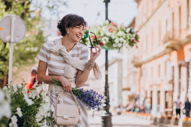 Mujer joven con flores caminando en la ciudad