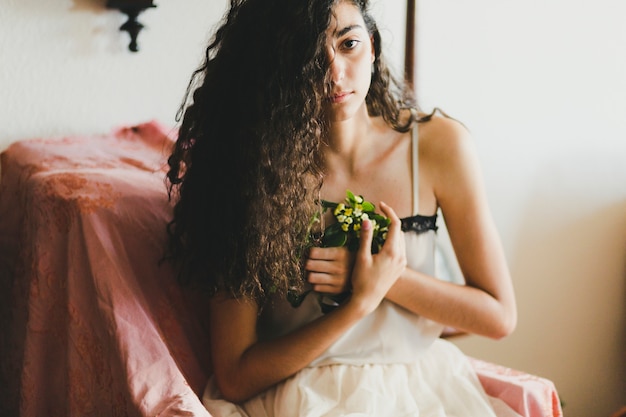 Mujer joven con flores mirando a cámara