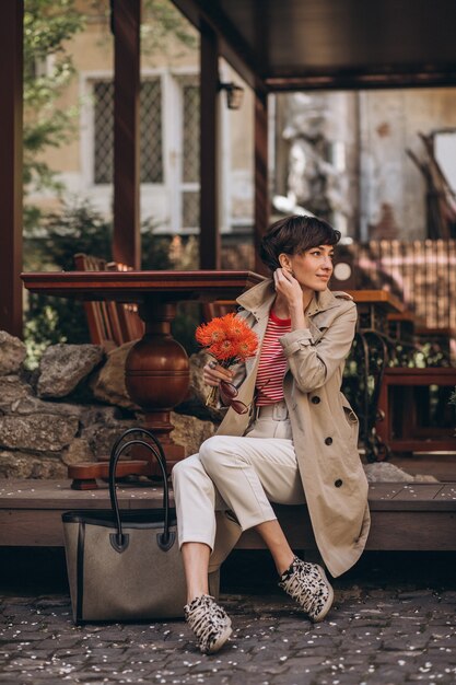 Mujer joven, con, flores, sentado, en la calle