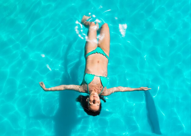 Mujer joven flotando en la espalda en la piscina