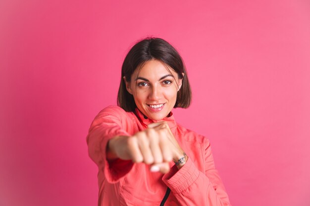 Mujer joven en forma en chaqueta de deporte en rosa lucha contra el gesto de la caja