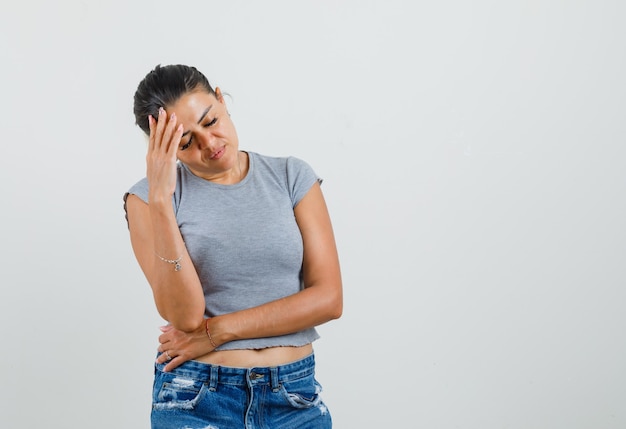 Foto gratuita mujer joven frotándose la frente en camiseta, pantalones cortos y luciendo agotada.