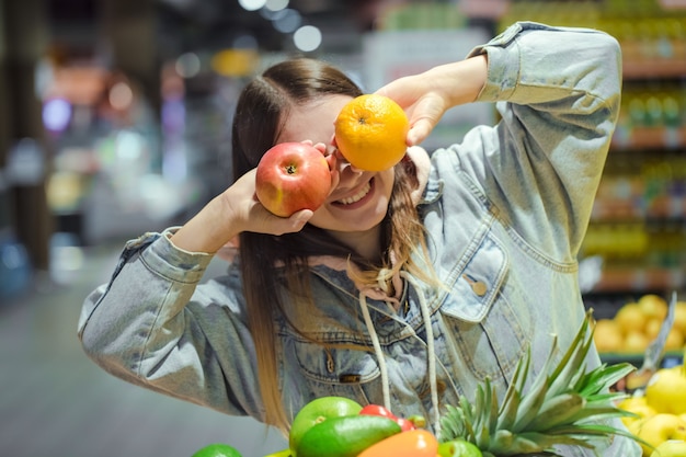 Mujer joven con fruta en sus manos en el supermercado.