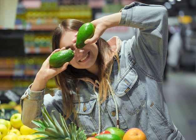 Mujer joven con fruta en sus manos en el supermercado.