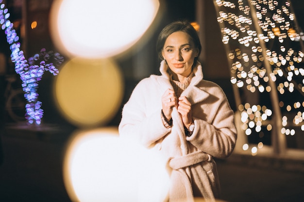 Mujer joven fuera de la calle de noche con luces