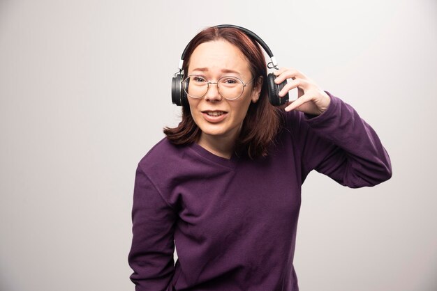 Mujer joven con gafas escuchando música en auriculares sobre un fondo blanco. Foto de alta calidad