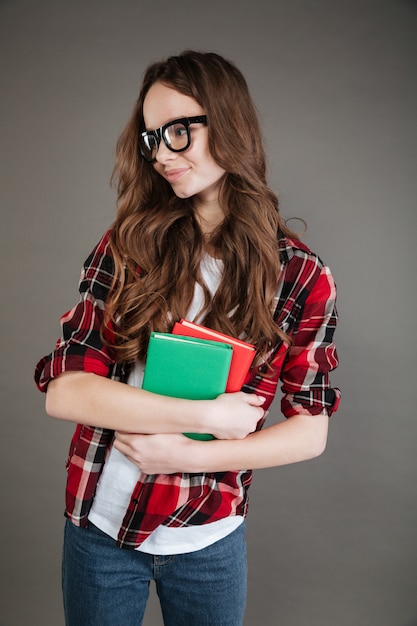 Mujer joven con gafas con libros en las manos.