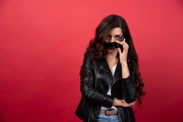 Mujer joven con gafas negras sobre un fondo rojo. Foto de alta calidad