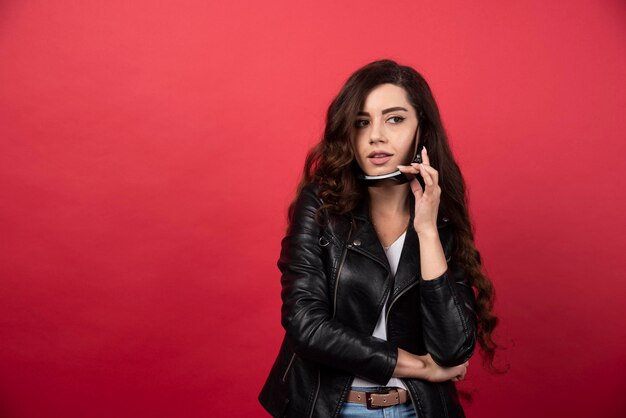 Mujer joven con gafas negras sobre un fondo rojo. Foto de alta calidad