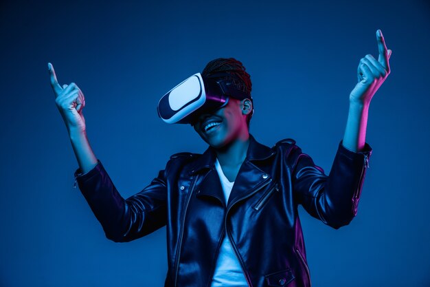 Mujer joven con gafas de realidad virtual con luces de neón