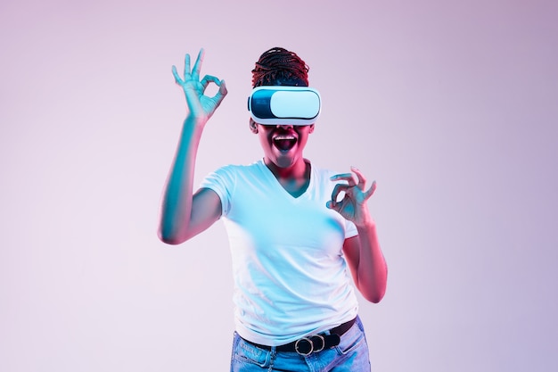 Mujer joven con gafas de realidad virtual con luces de neón