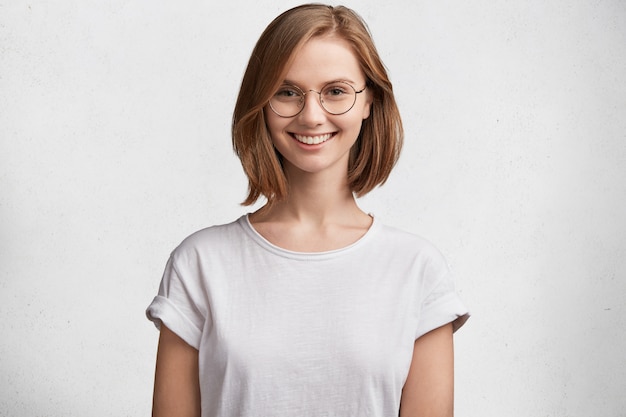 Mujer joven con gafas redondas y camiseta blanca