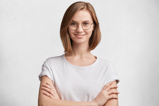 Mujer joven con gafas redondas y camiseta blanca