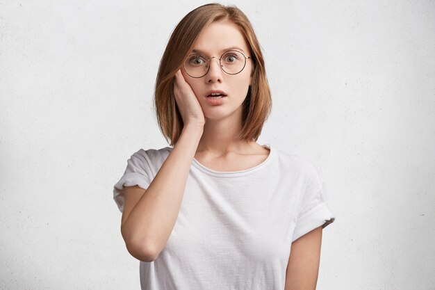 Mujer joven con gafas redondas y camiseta blanca