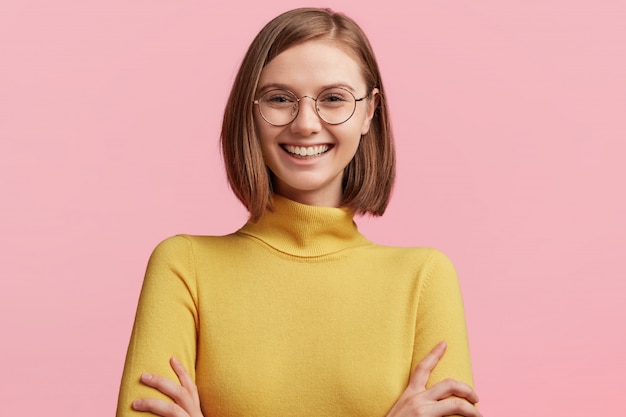 Mujer joven con gafas redondas y suéter amarillo