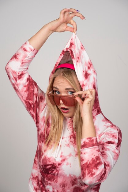 Mujer joven con gafas rosas tirando de su suéter.