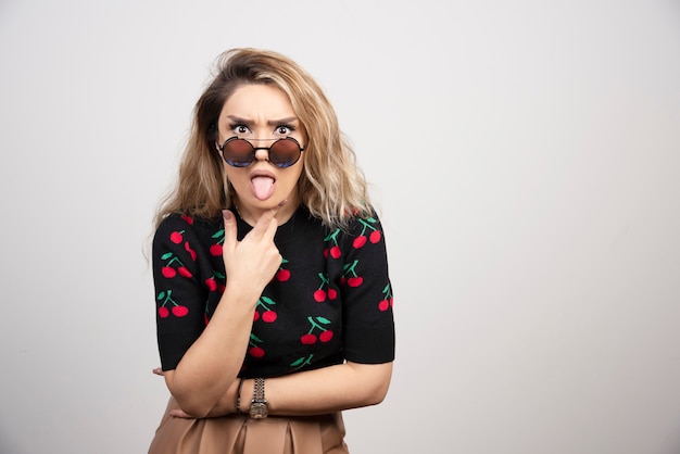 Mujer joven con gafas sacando la lengua.