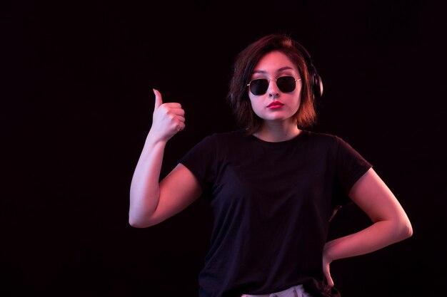 Mujer joven con gafas de sol y camiseta negra con auriculares