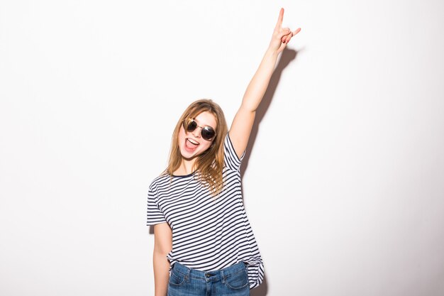 Mujer joven con gafas de sol dando el signo de Rock and Roll aislado en la pared blanca