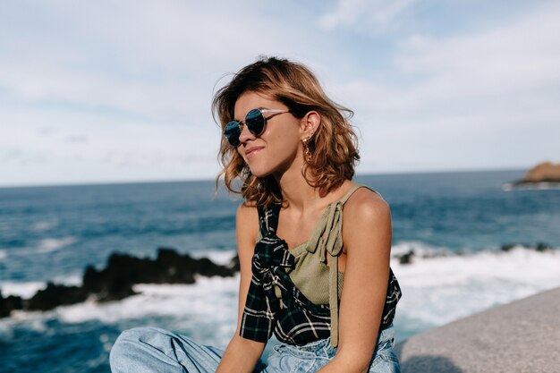 Mujer joven con gafas de sol posando en la playa