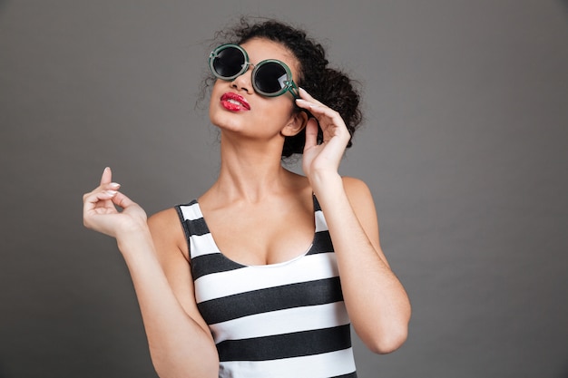 Mujer joven con gafas de sol y vestido a rayas