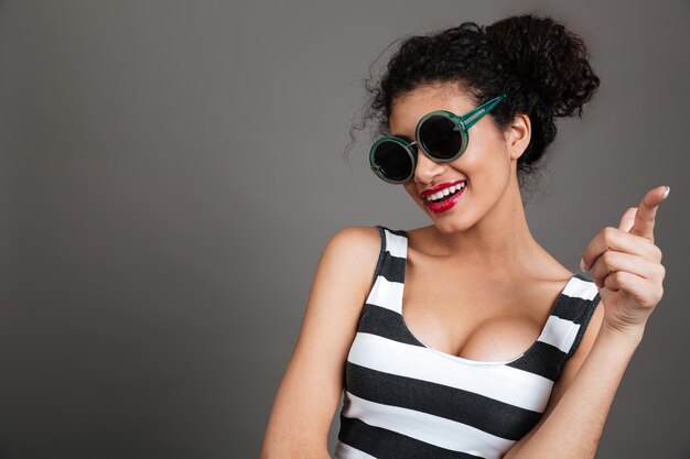 Mujer joven con gafas de sol y vestido a rayas