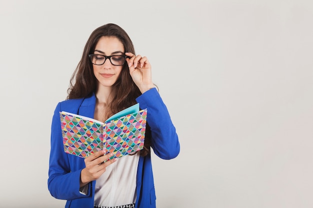 Foto gratuita mujer joven con gafas sujetando un cuaderno de colores